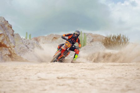 Téléchargez les photos : Jeune homme pratique l'équitation moto de saleté. Éclaboussures de sable - en image libre de droit