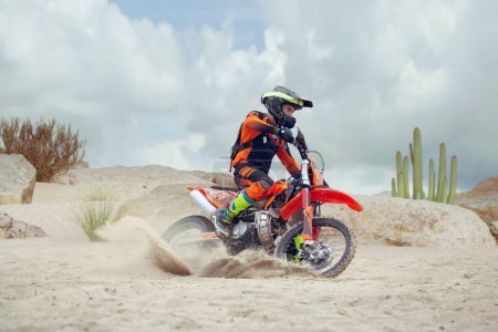 Téléchargez les photos : Jeune homme pratique l'équitation moto de saleté. Éclaboussures de sable - en image libre de droit