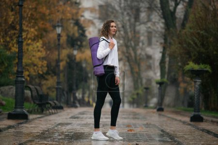 Téléchargez les photos : Une jeune femme qui s'entraîne dans un parc pluvieux. Femme jogger exercice à l'extérieur - en image libre de droit