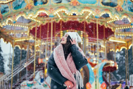 Téléchargez les photos : Jeune femme brune en chapeau blanc d'hiver marchant parc enneigé - en image libre de droit