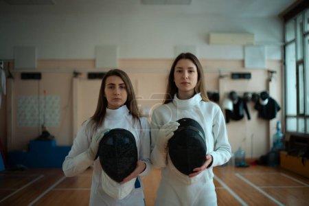 Téléchargez les photos : Escrime sportive. Deux filles escrimeurs posant dans le hall. - en image libre de droit