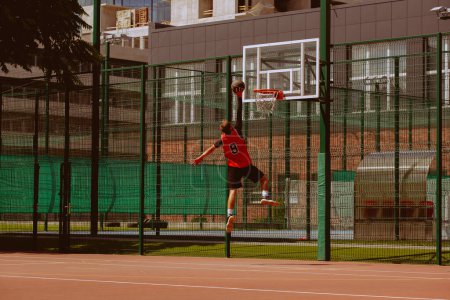 Téléchargez les photos : Joueur de basket masculin jouant au streetball pendant la journée chaude - en image libre de droit