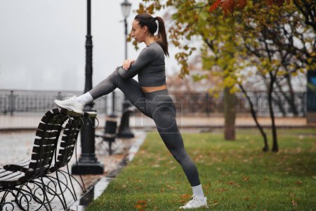 Photo for Young woman training in rainy park. Female jogger exercising outdoors - Royalty Free Image