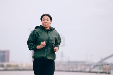 Foto de Mujer joven entrenando al aire libre. Deportiva chica corriendo en la ciudad - Imagen libre de derechos