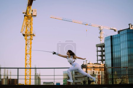 Fencer woman practice on a rooftop with the city in background 
