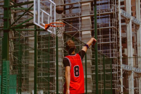 Téléchargez les photos : Joueur de basket masculin jouant au streetball pendant la journée chaude - en image libre de droit