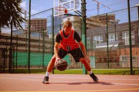 Foto de Jugador de baloncesto masculino jugando streetball durante el día caliente - Imagen libre de derechos