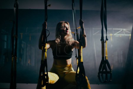 Téléchargez les photos : Jeune femme blonde avec formation de cheveux bouclés dans la salle de gym - en image libre de droit