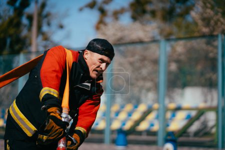 Photo for Firefighter training with hose on the sports ground. - Royalty Free Image