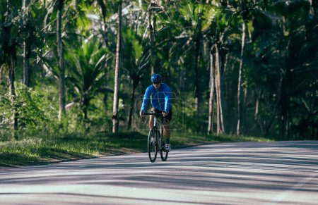 Téléchargez les photos : Jeune cycliste homme à vélo sur la route en forêt - en image libre de droit