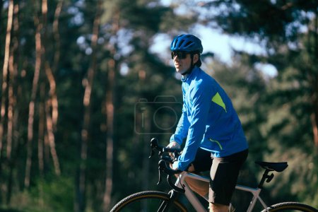 Téléchargez les photos : Jeune cycliste masculin avec vélo sur la route dans la forêt - en image libre de droit