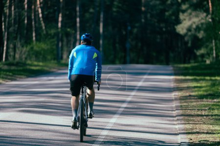 Téléchargez les photos : Mâle Cycliste promenades sur la route en forêt un jour d'été. - en image libre de droit