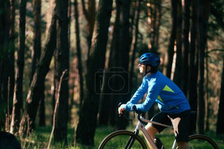 Téléchargez les photos : Un jeune homme en casque fait du vélo dans la forêt - en image libre de droit