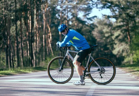 Téléchargez les photos : Cycliste masculin à vélo sur la route en forêt - en image libre de droit