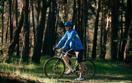 Téléchargez les photos : Bel homme vélo sur la route en forêt - en image libre de droit
