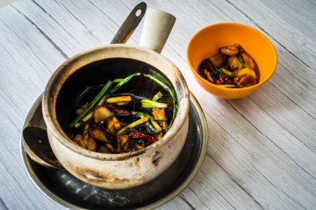 Photo for Stir fry frog leg with spring onions and dried reed chilli and served in a claypot - Royalty Free Image