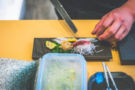 Photo for Hands of chef preparing sashimi raw fish in a japanese restaurant - Royalty Free Image