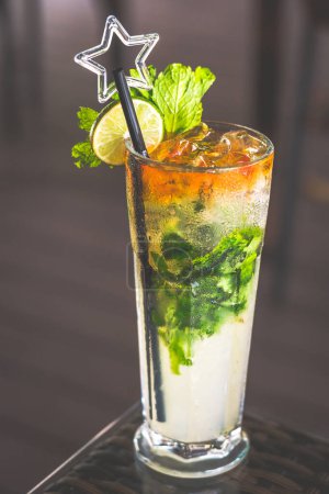 a mojito served in a tall glass with a straw and topped with a slice of lime