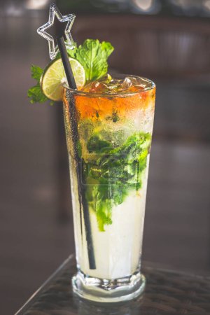 a mojito served in a tall glass with a straw and topped with a slice of lime