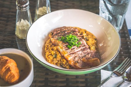 Photo for Risotto served with angus medium rare ribeye steak in a bowl - Royalty Free Image