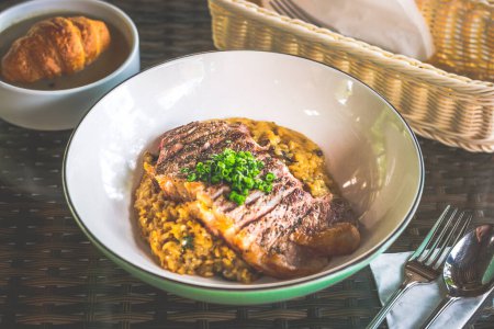 Photo for Risotto served with angus medium rare ribeye steak in a bowl - Royalty Free Image