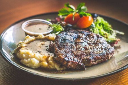 Photo for Ribeye steak with Mashed potato and gravy, mesclun salad and mushroom sauce - Royalty Free Image