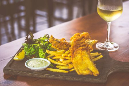 Beer Battered Fish & Chips with mesclun salad and tartar sauce and served on a wooden platter