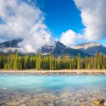 Mountain landscape at the day time. River and forest in a mountain valley. Natural landscape with a blue sky and clouds. Banff National Park, Alberta, Canada. 