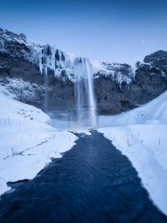 Photo for Seljalandsfoss waterfall, Iceland. Icelandic winter landscape.  High waterfall and rocks. Snow and ice. Powerful stream of water from the cliff. A popular place to travel in Iceland. - Royalty Free Image