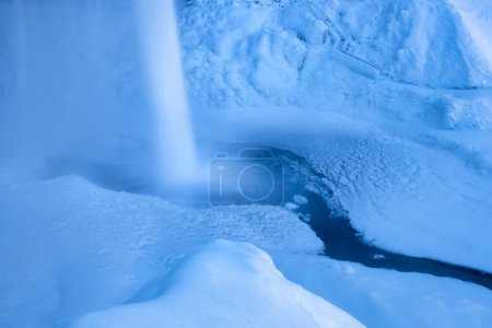 Téléchargez les photos : Cascade Seljalandsfoss, Islande. Paysage hivernal islandais. Haute cascade et rochers. Neige et glace. Puissant ruisseau d'eau de la falaise. Un endroit populaire pour voyager en Islande. - en image libre de droit