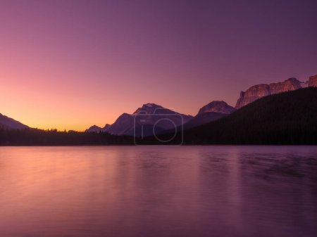 Photo for Mountain landscape at dawn. Sunbeams in a valley. Lake and forest in a mountain valley at dawn. Natural landscape with bright sunshine. High rocky mountains. Banff National Park, Alberta, Canada. - Royalty Free Image