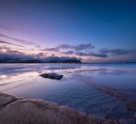 Téléchargez les photos : Un paysage marin au coucher du soleil dans les îles Lofoten, en Norvège. Du sable au bord de la mer. Ciel lumineux au coucher du soleil. Une plage de sable à marée basse. Longue exposition. Photo pour papier peint. - en image libre de droit