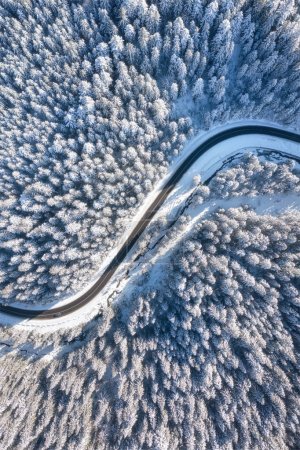 Foto de Vista aérea de la carretera y el bosque en invierno. Paisaje natural de invierno desde el aire. Frío invernal. Bosque y nieve. Paisaje de un dron. - Imagen libre de derechos