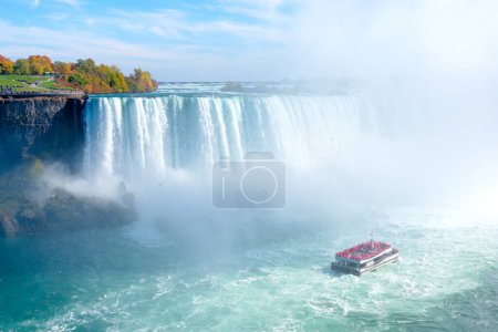 Téléchargez les photos : Niagara Falls. A pleasure boat with people near the huge famous waterfall. View from the Canadian side. A rainbow over the water on a sunny day. Nature scenery. Photo for advertising. - en image libre de droit