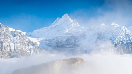 Téléchargez les photos : Nature. High mountain peaks above the clouds. Low clouds in the mountain valley. Clear skies and sharp rocks with glaciers. High mountain natural scenery. A place for hiking with a beautiful view. Lauterbrunner, Switzerland. - en image libre de droit