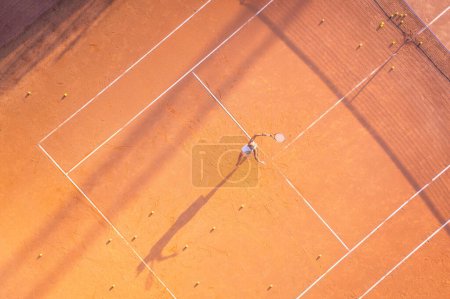 Foto de Estilo de vida saludable. Una joven juega al tenis en la cancha. La vista desde el aire en el jugador de tenis. Corte sucia. Fondo deportivo. Vista aérea desde el dron. - Imagen libre de derechos