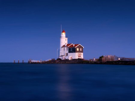 Photo for A lighthouse on the beach during blue hour. A landmark in maritime navigation. Long exposure. Natural composition. Photo for wallpaper and background. Paard van Marken, Netherlands. - Royalty Free Image