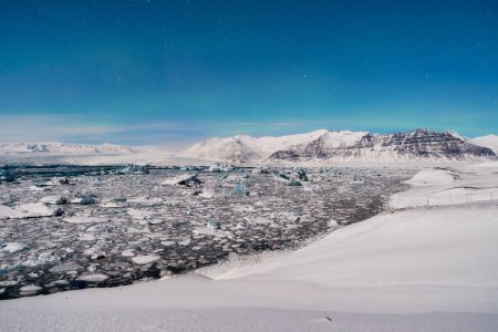 Foto de Paisaje nocturno en Islandia. El hielo como fondo. Parque Nacional Vatnajokull. Vista de la laguna de hielo. Paisajes invernales en Islandia. Fondo natural. País del norte. - Imagen libre de derechos