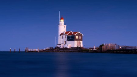 Photo for Paard van Marken, Netherlands. A lighthouse on the beach during blue hour. A landmark in maritime navigation. Long exposure. Photo for wallpaper and background. - Royalty Free Image