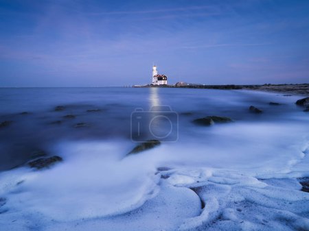 Photo for A lighthouse on the beach during blue hour. A landmark in maritime navigation. Long exposure. Natural composition. Photo for wallpaper and background. Paard van Marken, Netherlands. - Royalty Free Image
