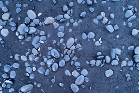 Foto de Arena negra y guijarros como fondo. Piedras redondas en la playa. Fotografía para el diseño. Texturas en la naturaleza. - Imagen libre de derechos
