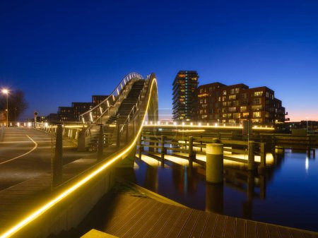 A bridge in the city at night. City lights. The Galaxy Bridge, Purmerend, Netherlands. The bridge on the blue sky background during the blue hour. Architecture and design. 