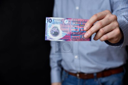 Empresario sosteniendo billetes en su mano. Hong Kong dólares en efectivo.