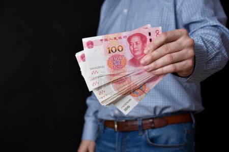 Photo for Businessman holding banknotes in his hand. Chinese RMB cash. - Royalty Free Image