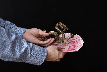 Geschäftsmann mit Geldscheinen in der Hand. Chinesisches RMB-Bargeld und symbolischer Drache.