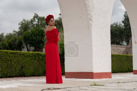 Photo for Frida-Inspired Essence: A Mexican woman, reminiscent of Frida Kahlo, graces an aged chair beneath delicate archways. Bathed in a play of light and shadow, her traditional attire and contemplative gaze - Royalty Free Image