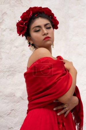 Foto de Esencia inspirada en Frida: Una mujer mexicana, que recuerda a Frida Kahlo, adorna una silla envejecida debajo de arcos delicados. Bañada en un juego de luz y sombra, su atuendo tradicional y su mirada contemplativa - Imagen libre de derechos