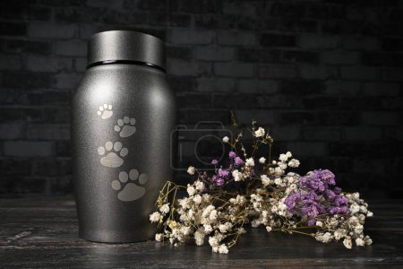 Photo for In remembrance of a pet. Pet urn beside a flower bouchet. - Royalty Free Image