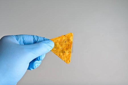 Photo for Gloved hand holding a hot tortilla chip for hot chip challenge. Horizontal image. - Royalty Free Image