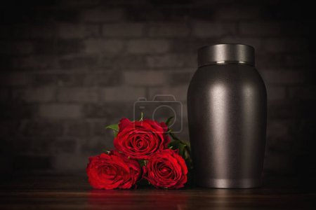 Funeral mourning urn next to a bunch of roses.